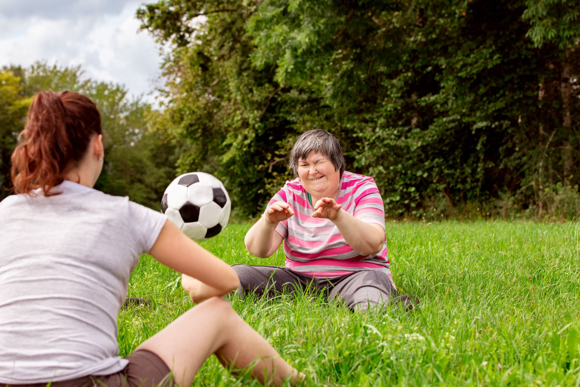 Two women in a park playing catch with a football