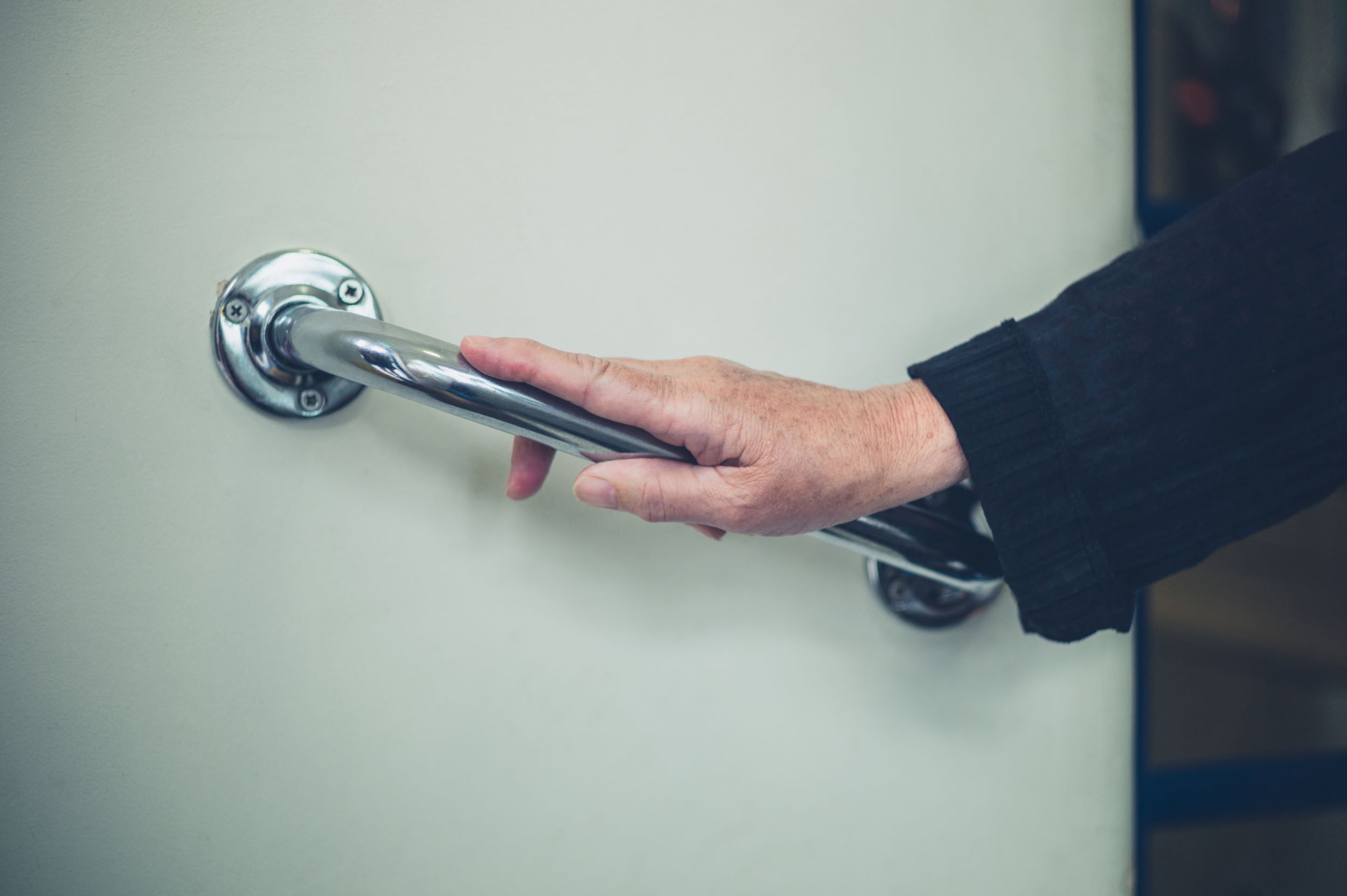 A hand holding a metal grab rail