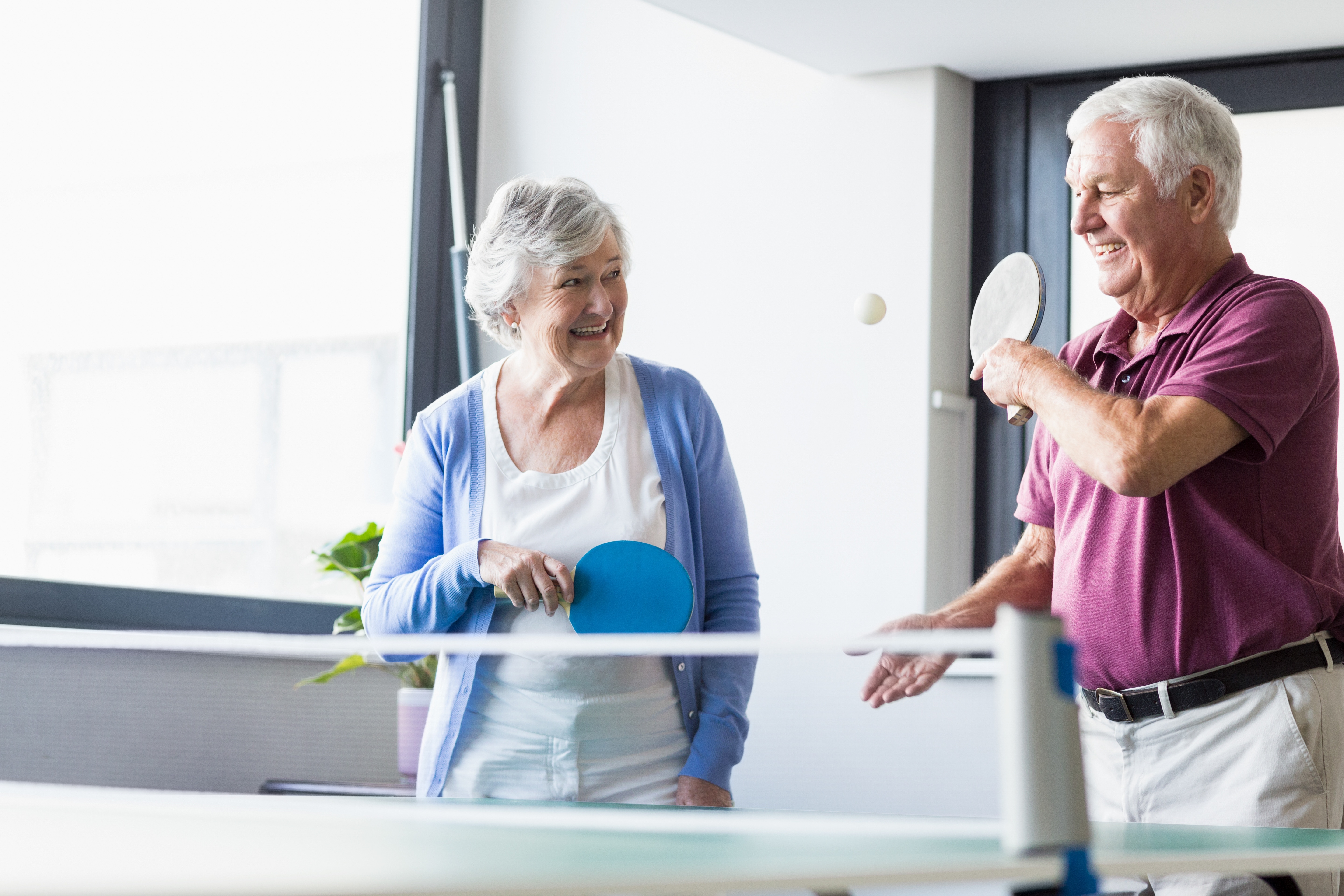 An older couple, playing table tennis 
