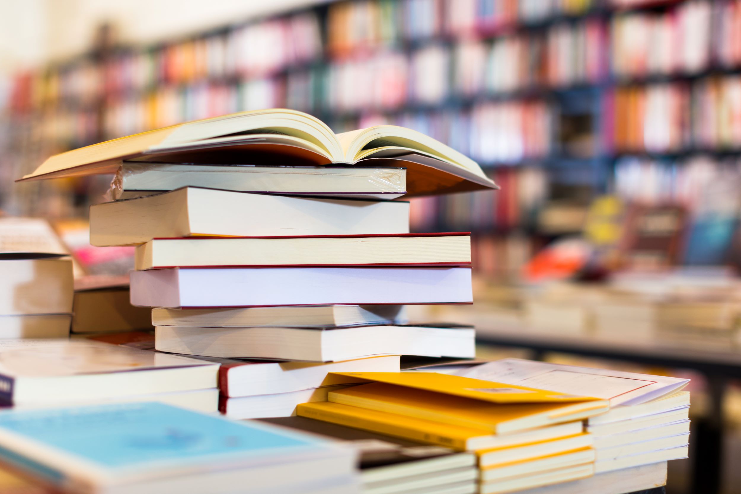A pile of books in a library, the one on top is open