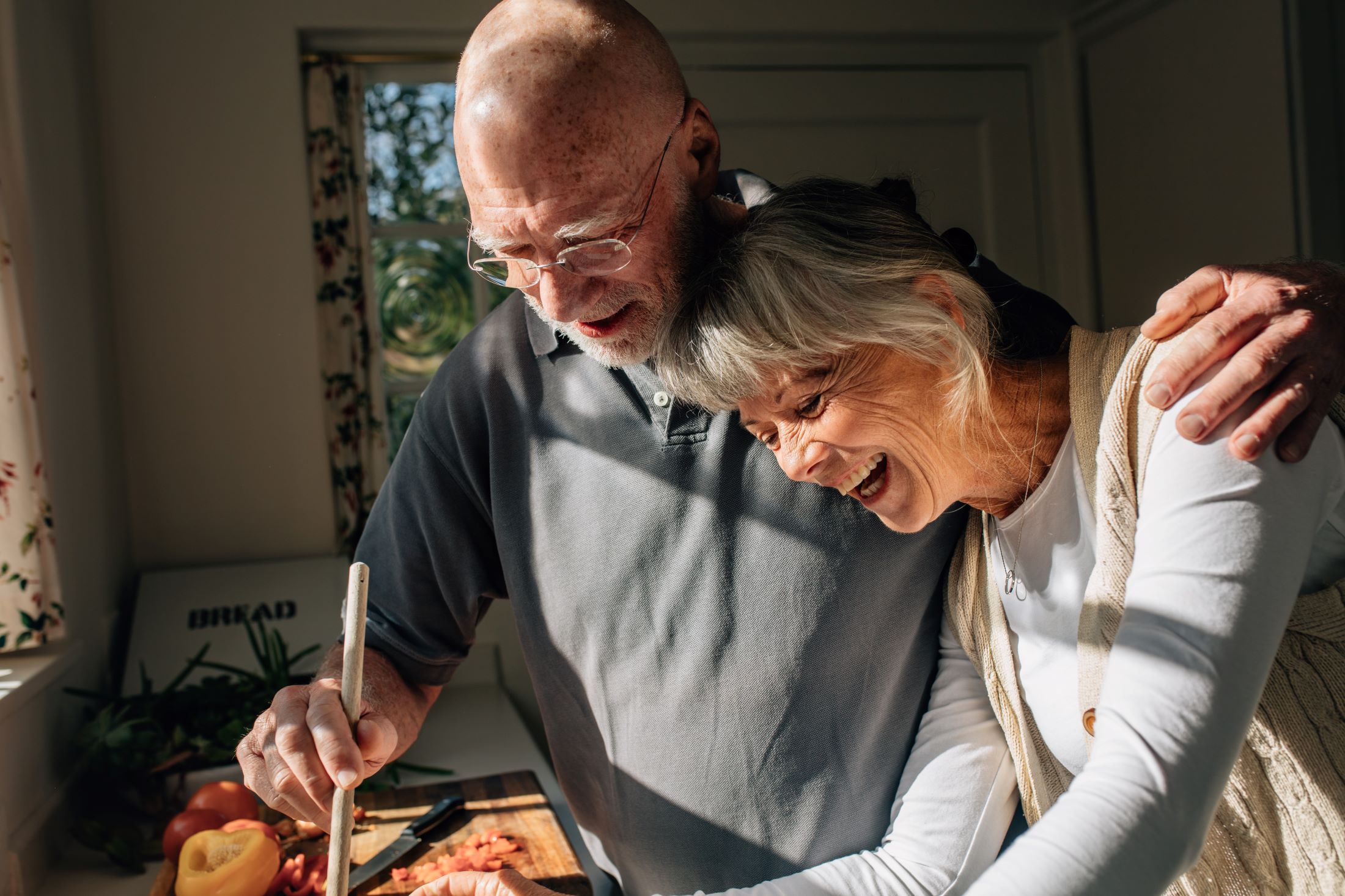 man with arm on womans shoulder in the kitchen prepping food