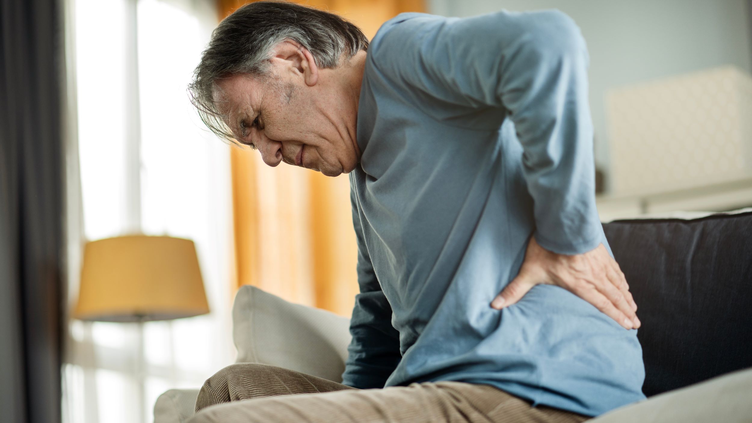 An older man in pain with his hand on his lower back