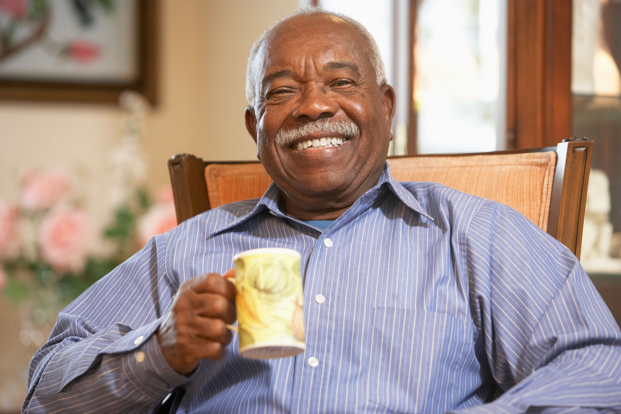 A cheerful smiling man holding a mug of tea
